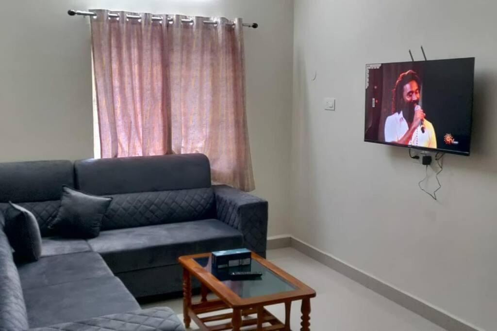 een woonkamer met een bank en een tv aan de muur bij Servostay Hafeezpet - 2 Bhk Fully Furnished Flat at Ground Floor in Hyderabad