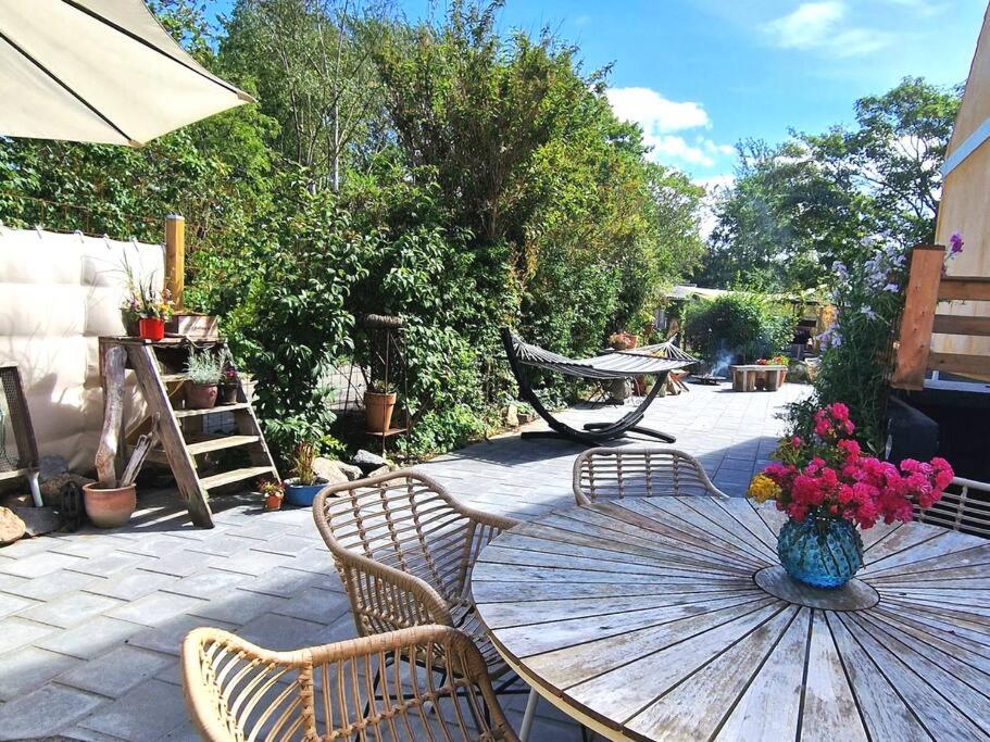 a patio with a table and chairs and an umbrella at Det Gamle Garnbinderi, ved Møns bedste strand. in Borre