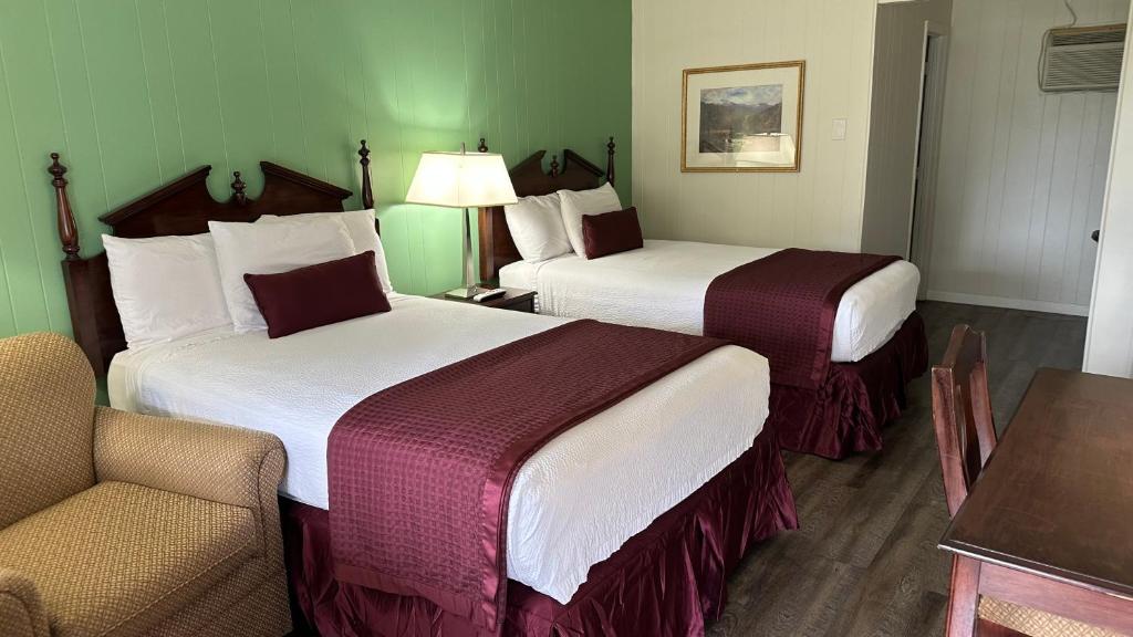 una habitación de hotel con 2 camas y una silla en Colonial Inn Franklin, en Franklin