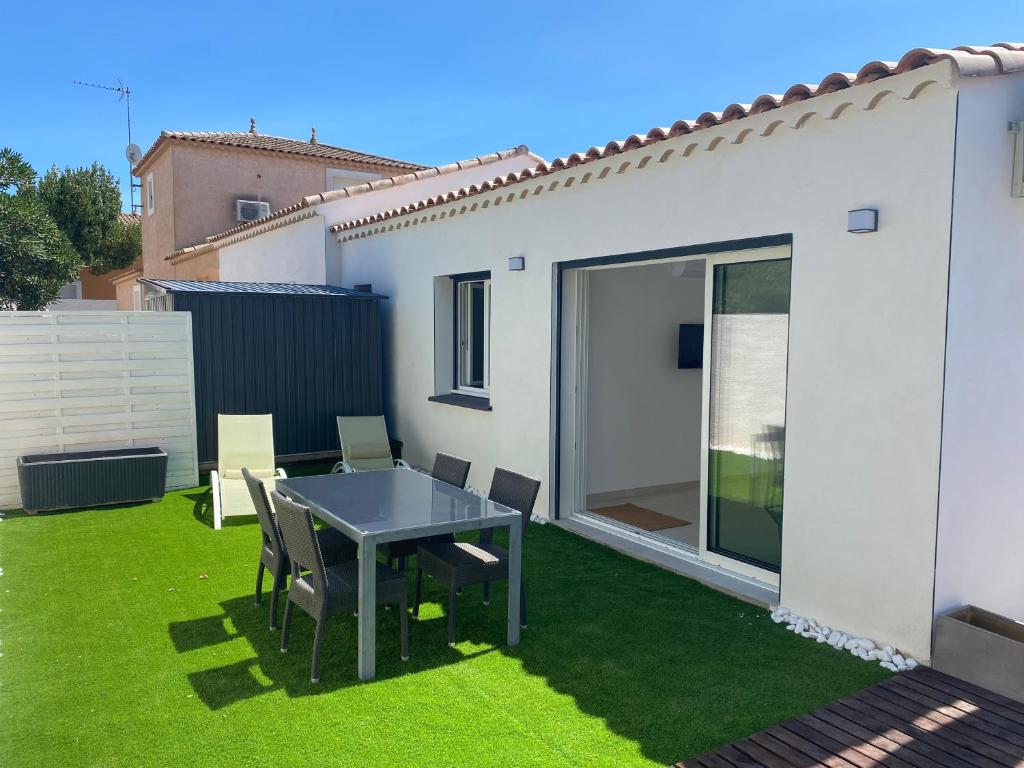 um pátio com uma mesa e cadeiras na relva em JOLIE MAISON A 700M DE LA MER em Le Grau-dʼAgde