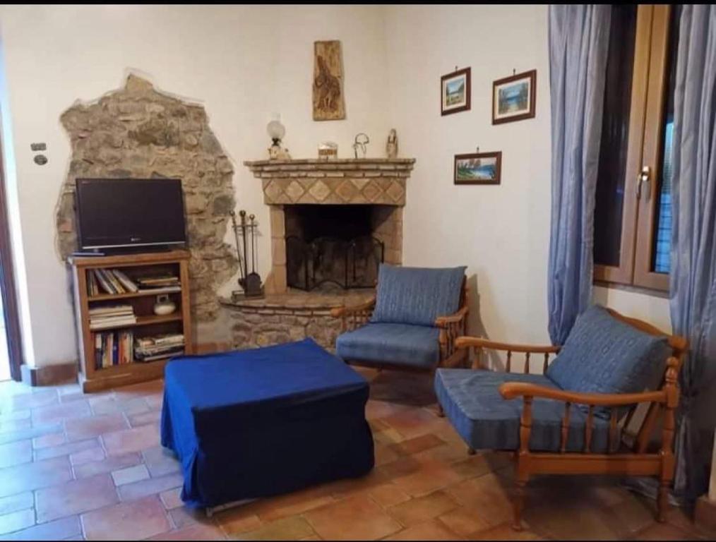 uma sala de estar com lareira de pedra e 2 cadeiras em Casa lago di Bolsena em Bolsena