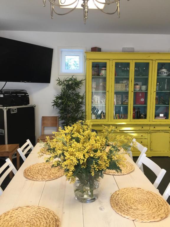 a dining room table with yellow flowers in a vase at Casa Acougo, Sarria in Sarria