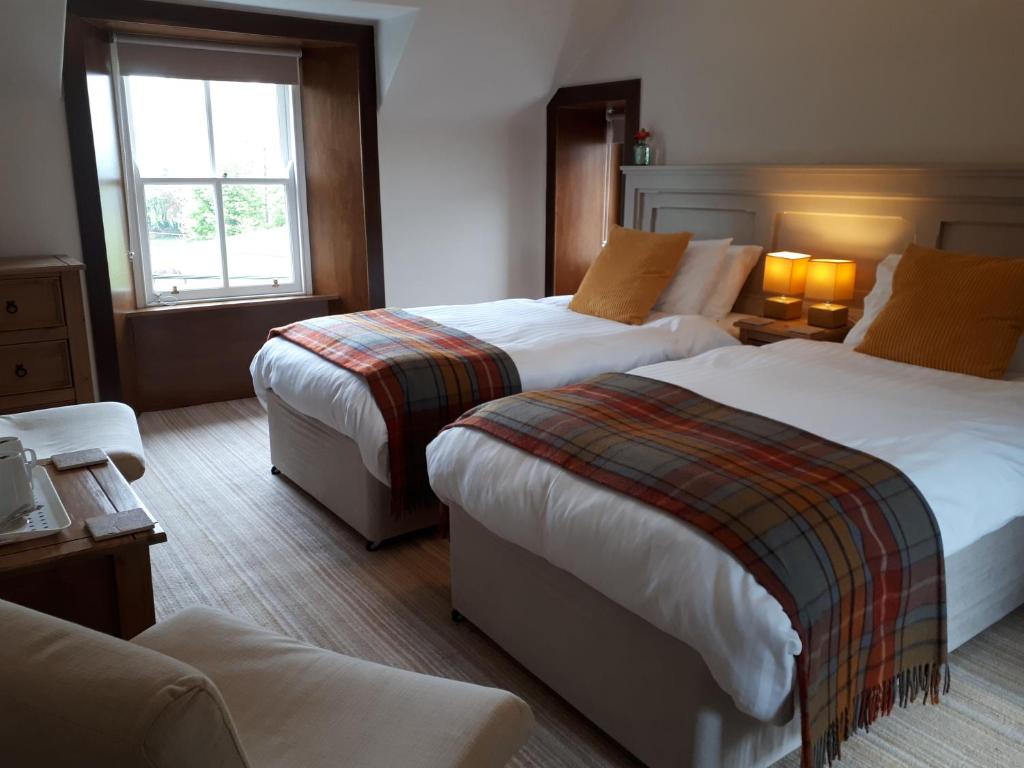 a hotel room with two beds and a window at Corsewall Arms Guest House in Stranraer