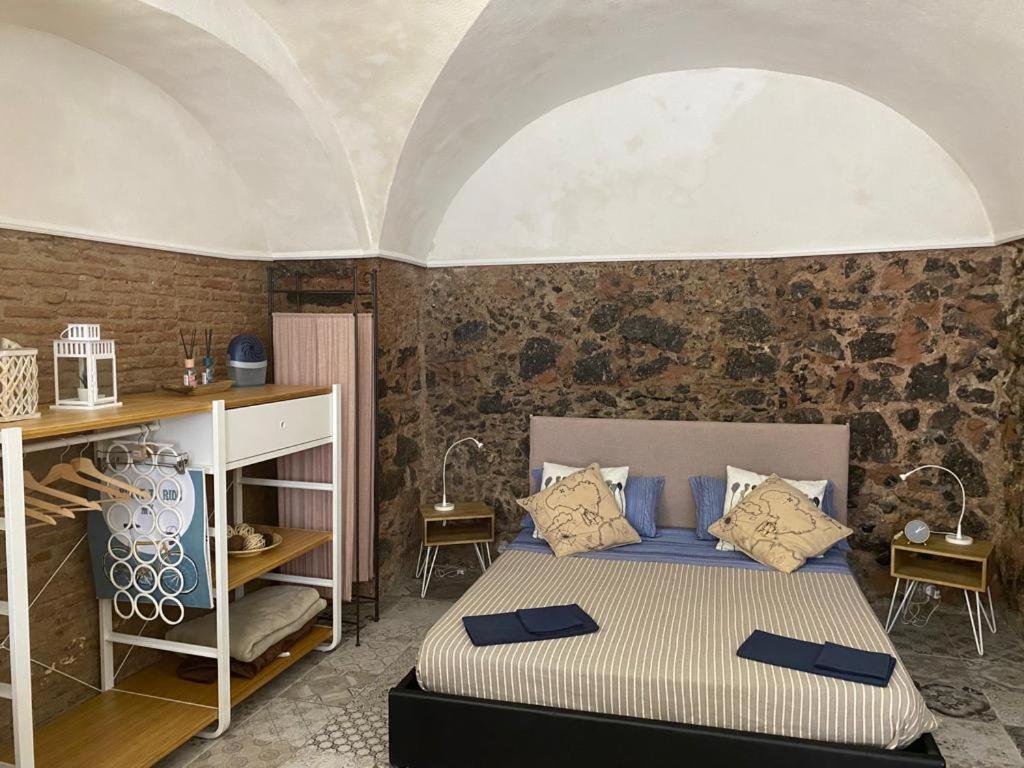 sypialnia z łóżkiem i ceglaną ścianą w obiekcie La Piccola Grotta Ursino w Katanii