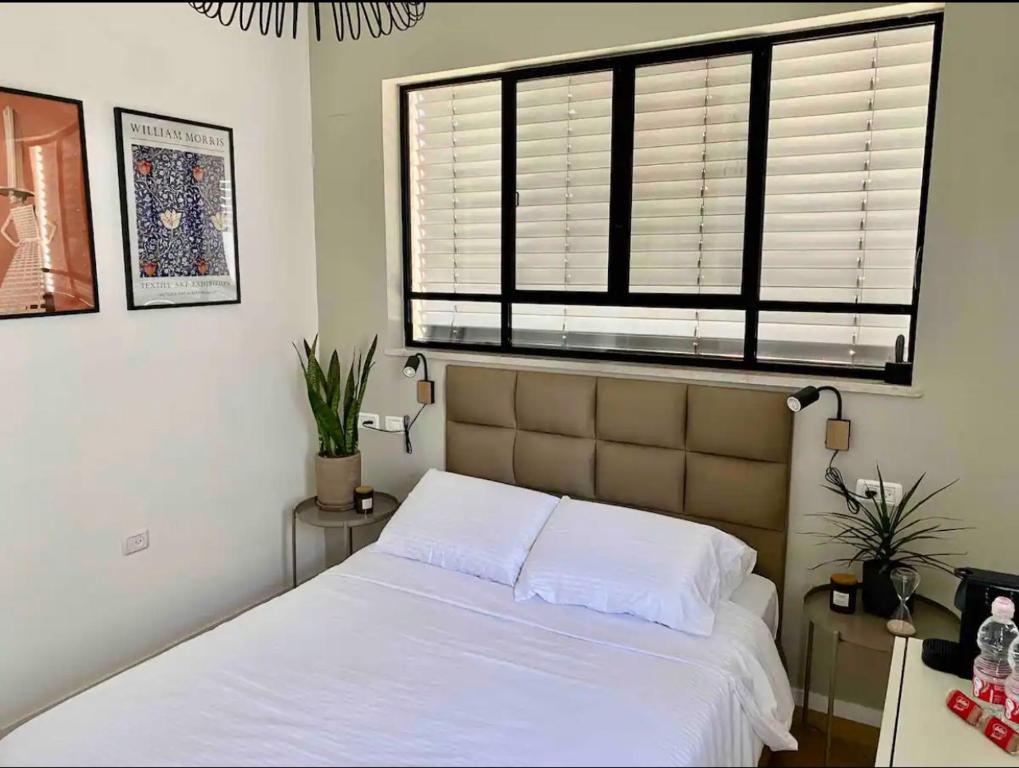 1 dormitorio con cama blanca y ventana en חדר סטודיו בסגנון נורדי en Sede Naẖum