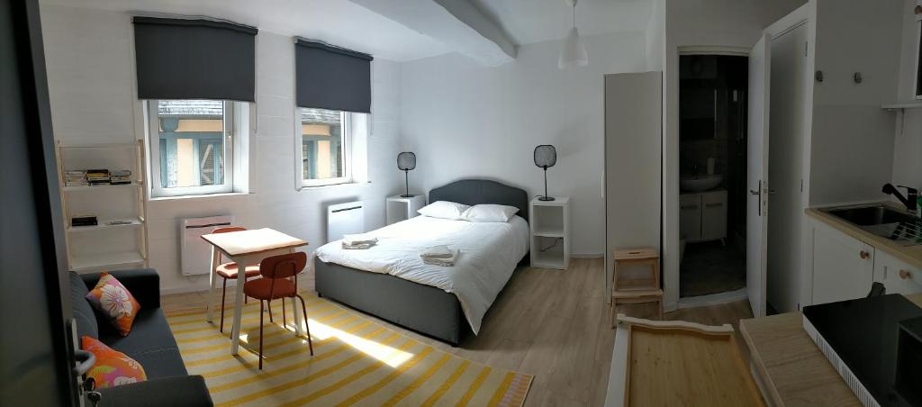 a bedroom with a bed and a table and a kitchen at Le 1 St Yves Studios in Tréguier