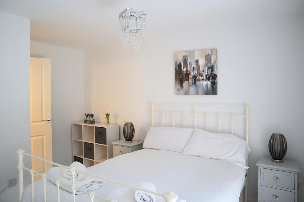 1 dormitorio con cama blanca y lámpara de araña en Lower Brook Mews, en Ipswich
