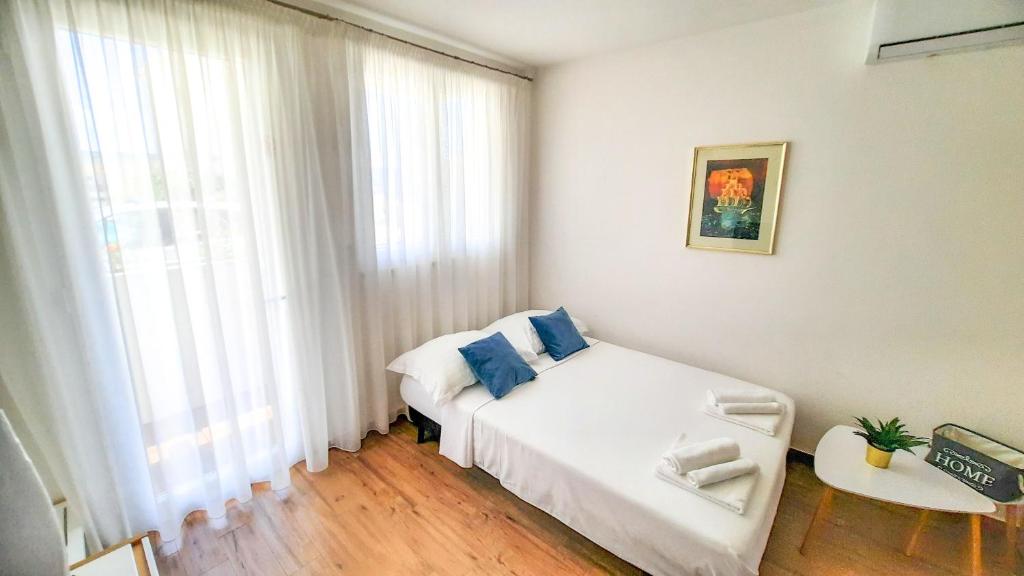 een kleine slaapkamer met een wit bed en een raam bij Studio apartman Kiara in Bol