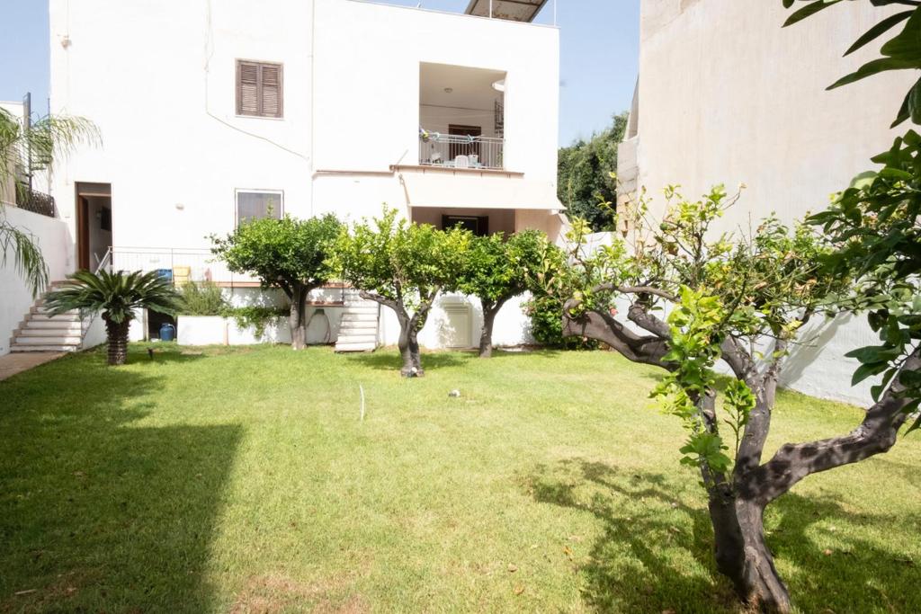 einen Hof mit Bäumen vor einem weißen Gebäude in der Unterkunft Casa Lisa a due passi dal mare con ampio giardino in San Vito lo Capo