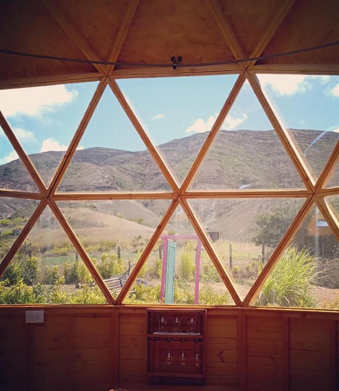a room with a large window with mountains in the background at Los Nopales Glamping in Sáchica