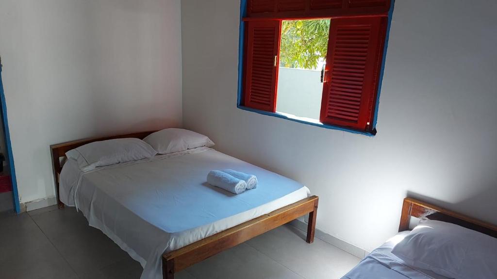 a bedroom with a bed and a window with red shutters at CASA TROPICANA - ITAÚNAS Centro in Itaúnas