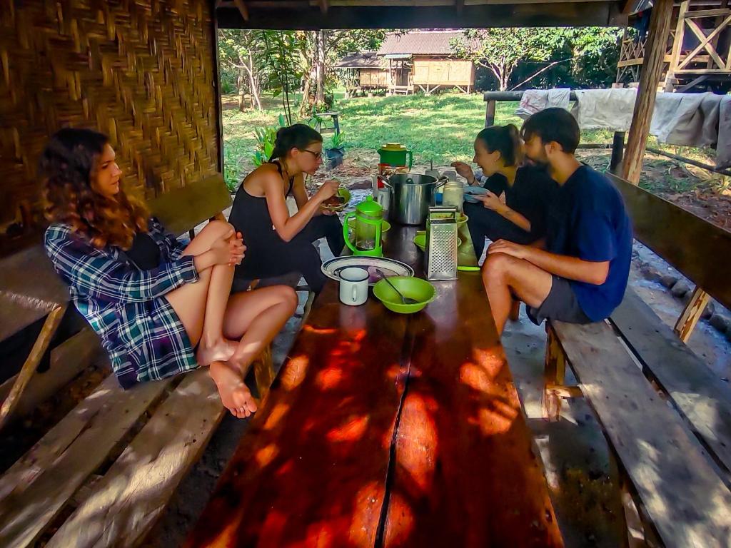 a group of people sitting around a wooden table at Wild Camp in Timbanglawang