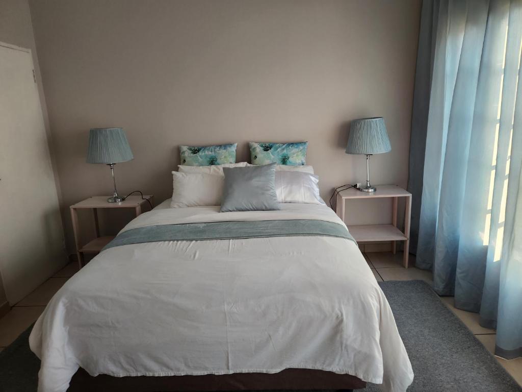 a bedroom with a large white bed with two lamps at Sunny Guest Room in Boksburg