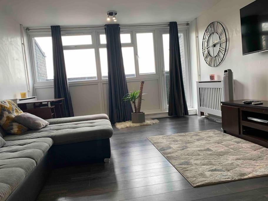 a living room with a couch and a clock on the wall at Two bed flat stylishly furnished in Purfleet