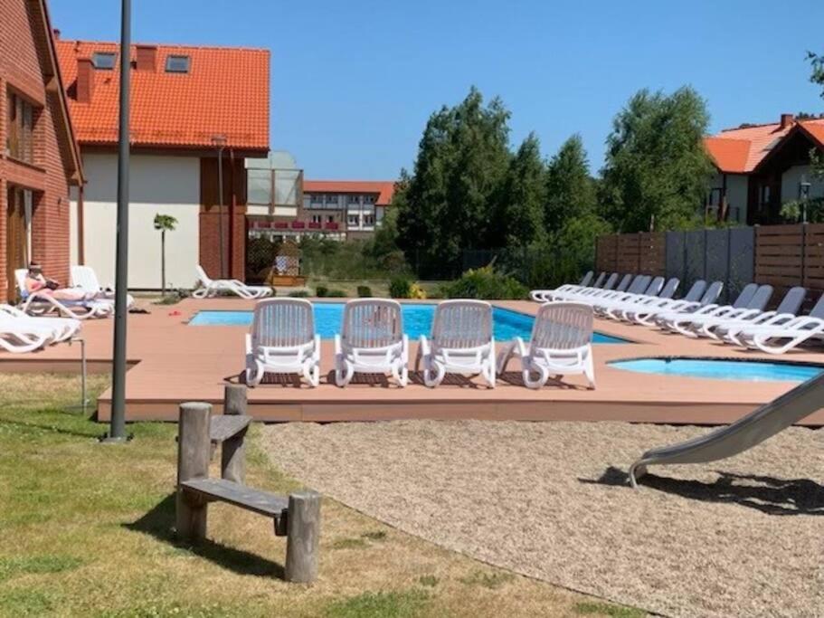 - un groupe de chaises blanches installées à côté de la piscine dans l'établissement PIASKOWA ŁEBSKA OSTOJA - Local 7, à Żarnowska