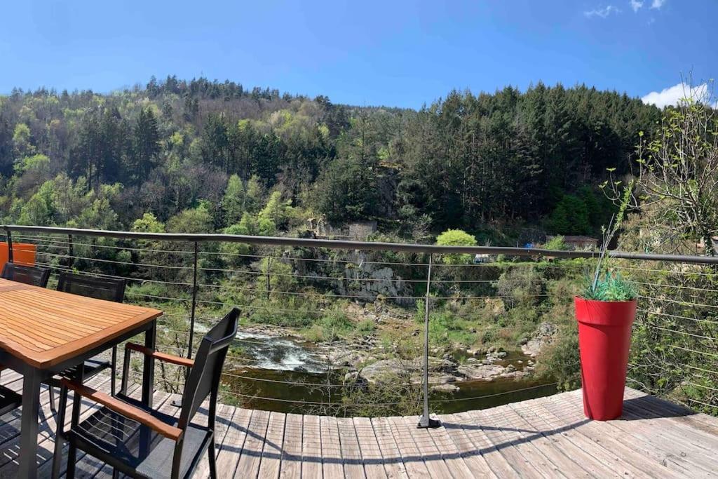 a balcony with a table and a view of a river at Le gîte de Moulinas in Giffon