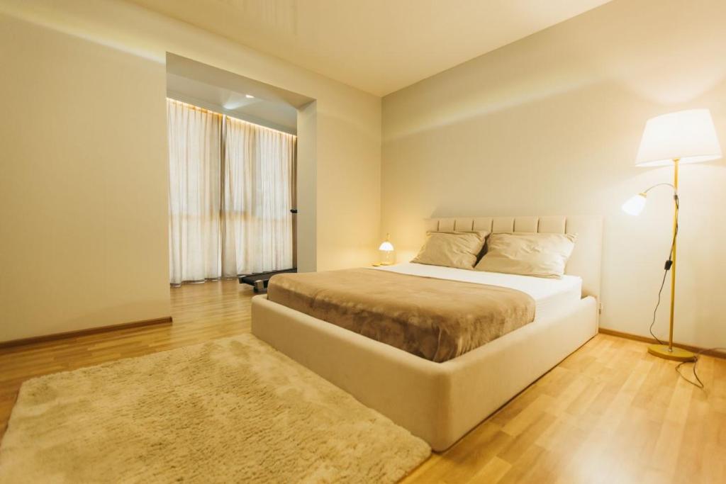 1 dormitorio con cama, lámpara y alfombra en Atlant luxury Big Family Apart on Golovna з двома окремими спальнями навпроти ТЦ ДЕПОТ БЕЗКОНТАКТНЕ ЗАСЕЛЕННЯ, en Chernivtsi