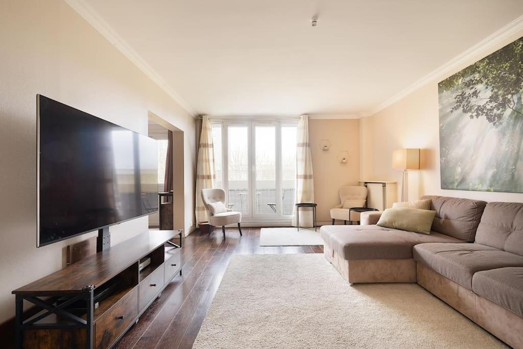 sala de estar con sofá y TV de pantalla plana en Location chic 3 chambres proche Paris & Disneyland, en Neuilly-sur-Marne
