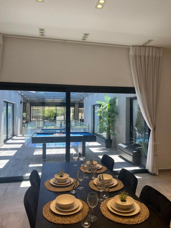 - une salle à manger avec une table, des chaises et une piscine dans l'établissement Luxurious house in Ness Tziona, à Nes Ẕiyyona