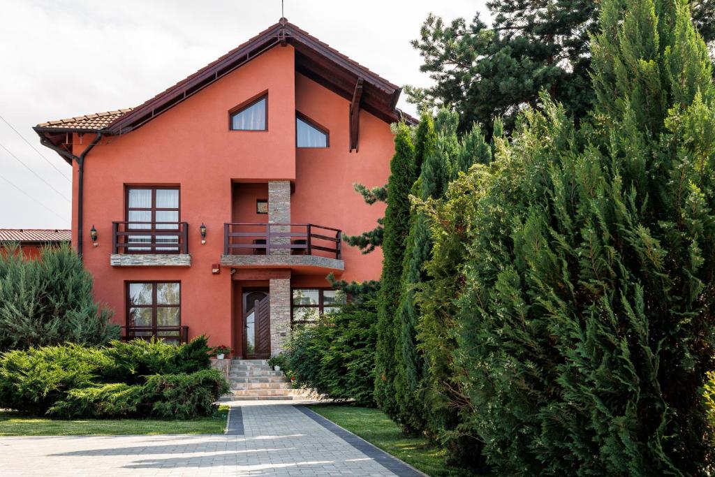 a red house with trees and bushes in front of it at Pensiunea Tanita in Bran