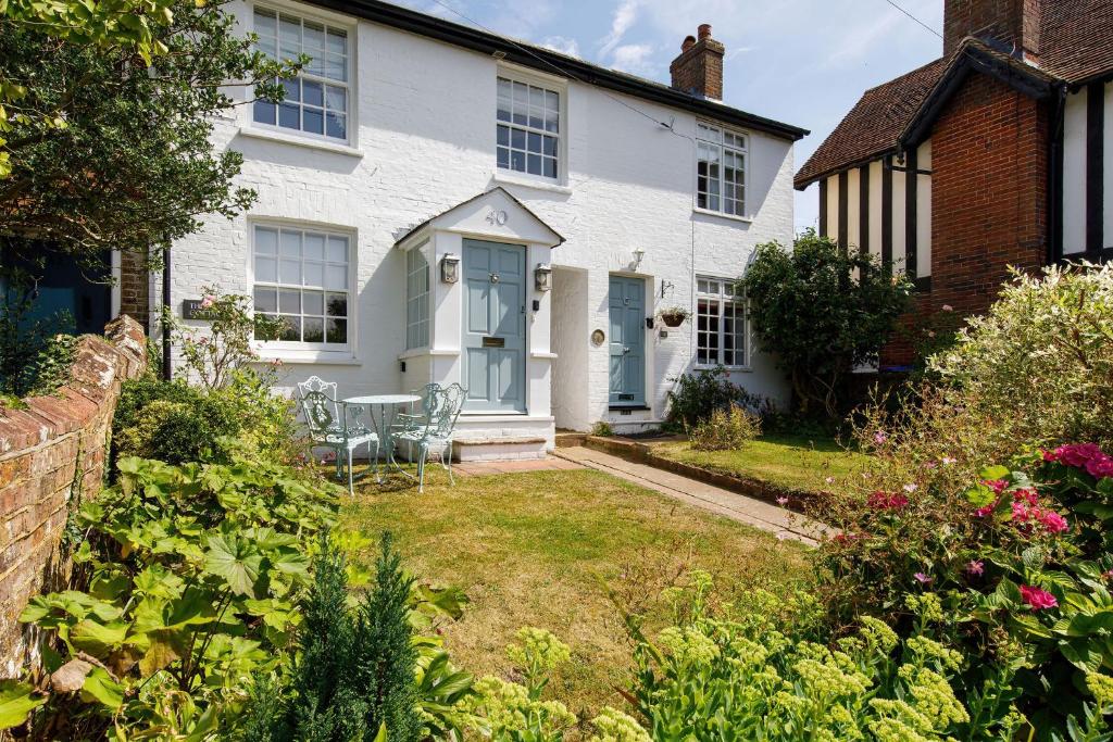 Casa blanca con mesa y sillas en el patio en The Kept Cottage en Hassocks