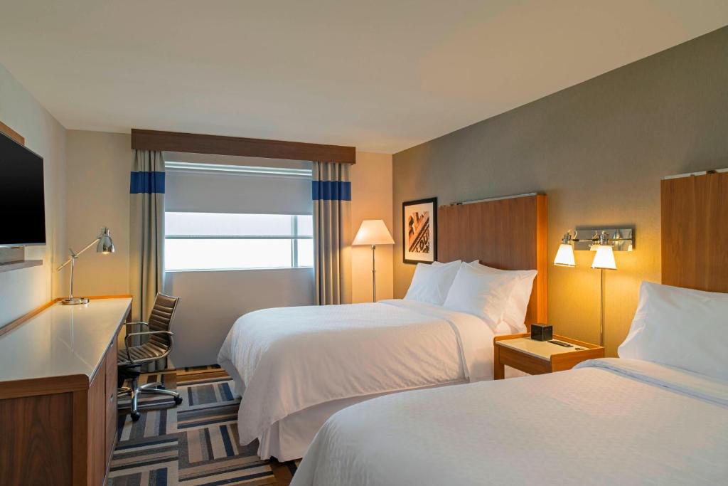 a hotel room with two beds and a flat screen tv at Four Points by Sheraton Midland in Midland