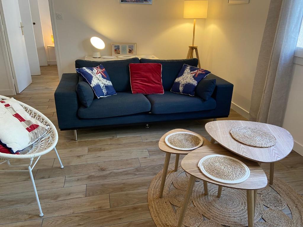 uma sala de estar com um sofá azul e duas mesas em COSY CONFORT LA PEROUSE 1A coeur de ville et plage em Concarneau