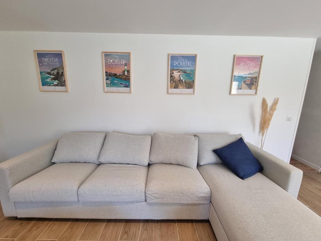 - un canapé dans un salon avec des affiches murales dans l'établissement MAMGOZ, à Clohars-Carnoët