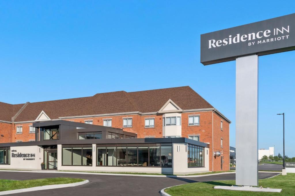 a red brick building with a sign in front of it at Residence Inn by Marriott Laval in Laval