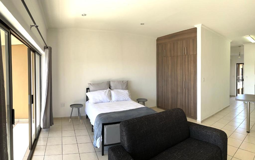 een slaapkamer met een bed en een bank bij H&H Self-catering in Windhoek