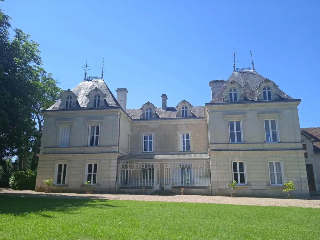 een groot huis met een grasveld ervoor bij Chateau de Maisonneuve 