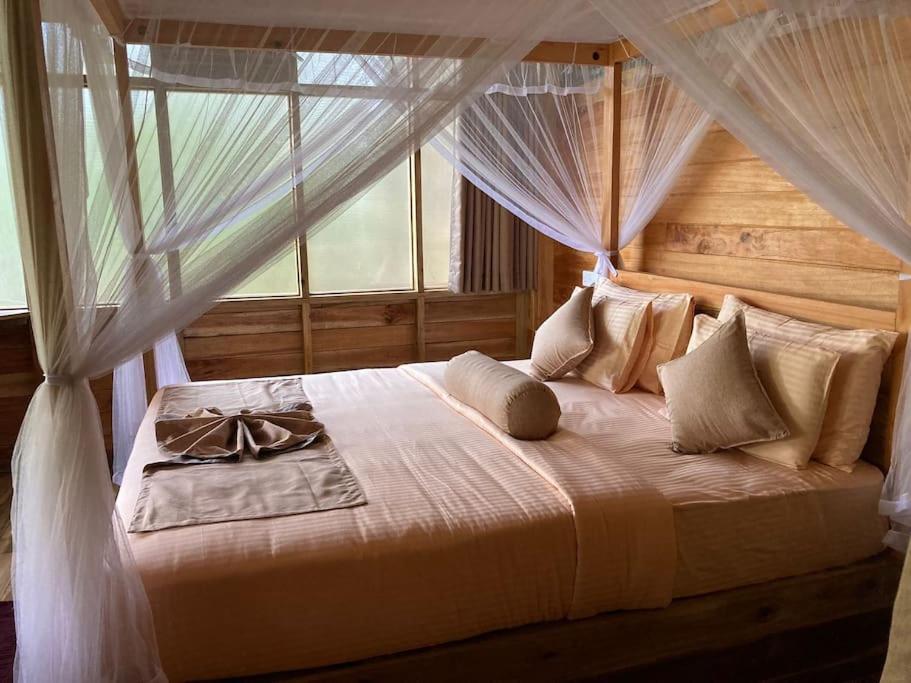 a bedroom with a canopy bed with a window at Treehouse in Ella