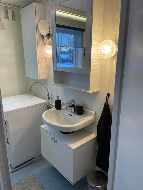 a white bathroom with a sink and a window at Litet hus på landet 