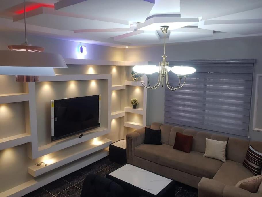 Il comprend un salon doté d'un canapé et d'une télévision à écran plat. dans l'établissement 3JD Lavishly Furnished 1-Bed Apt, à Lagos