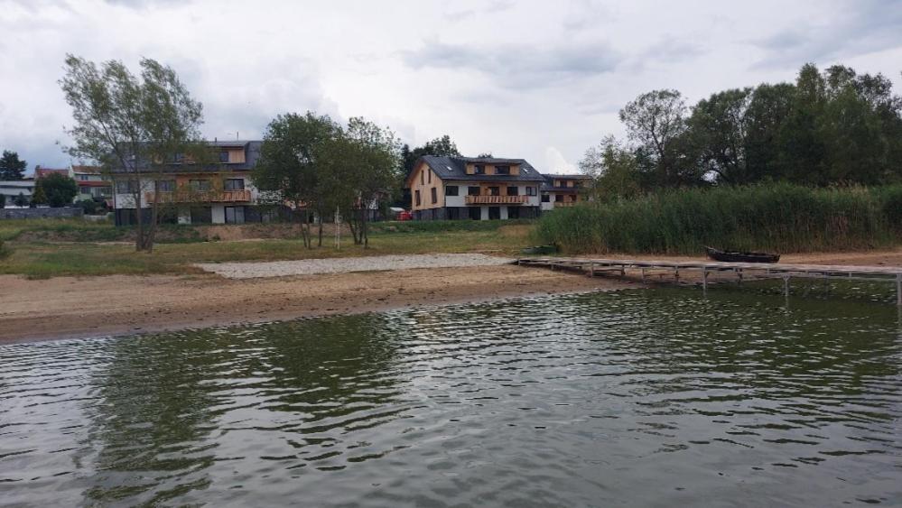 a large body of water with houses in the background at Lipno Apartments BERGMAX, Ski Areál Lipno 16min dojezd - Resort Malé Lipno s terasou a zahrádkou, parking free in Černá v Pošumaví