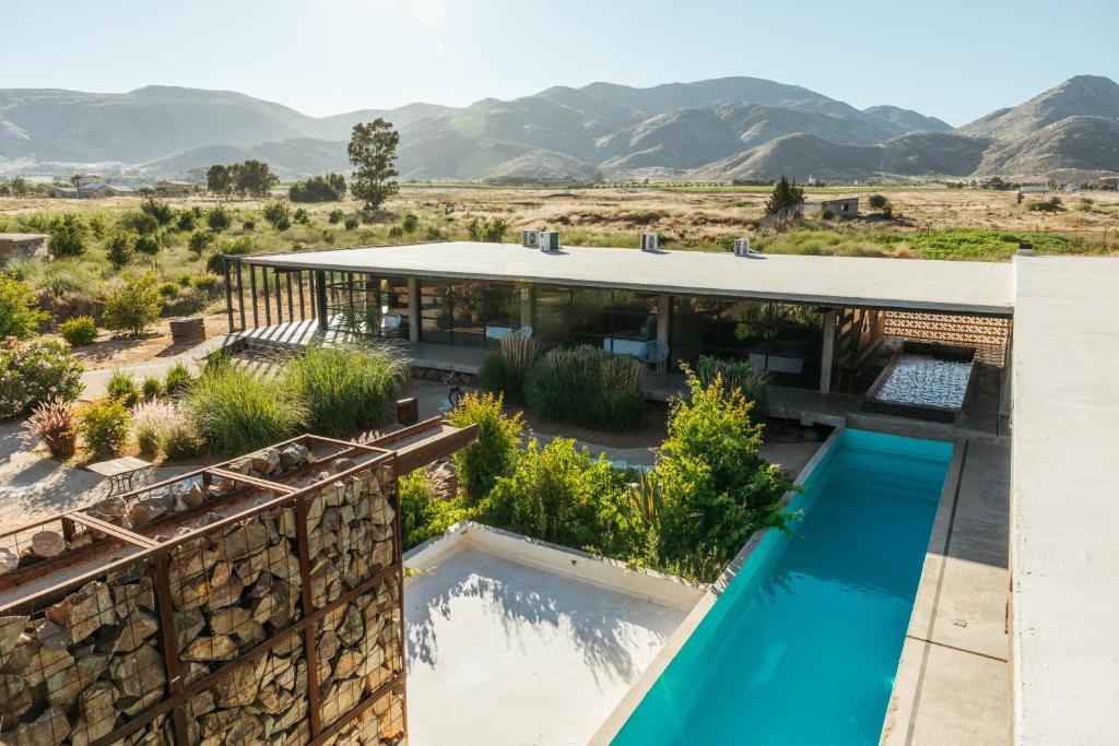 une maison avec une piscine et des montagnes en arrière-plan dans l'établissement Hotel Los Amantes Valle de Guadalupe, à Valle de Guadalupe