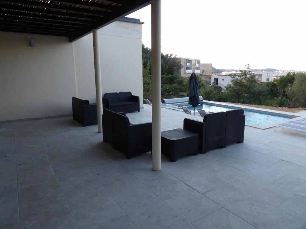 a patio with chairs and an umbrella next to a pool at Villa de standing in Calvi