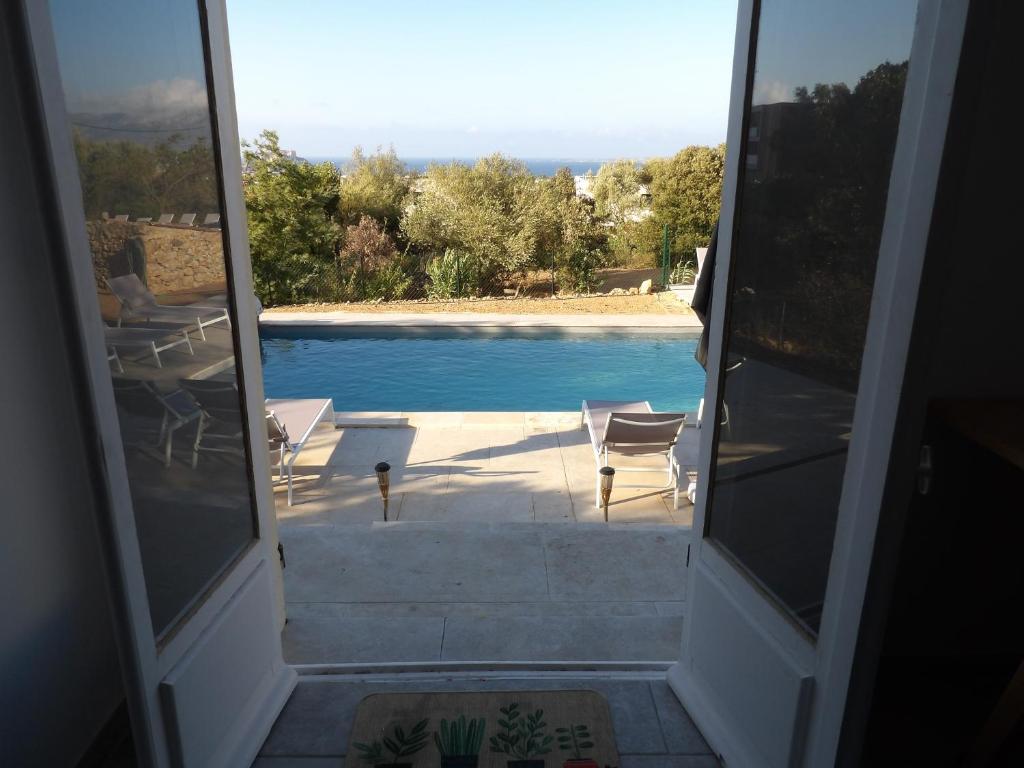 - une vue sur la piscine depuis la porte d'une maison dans l'établissement Villa de standing, à Calvi