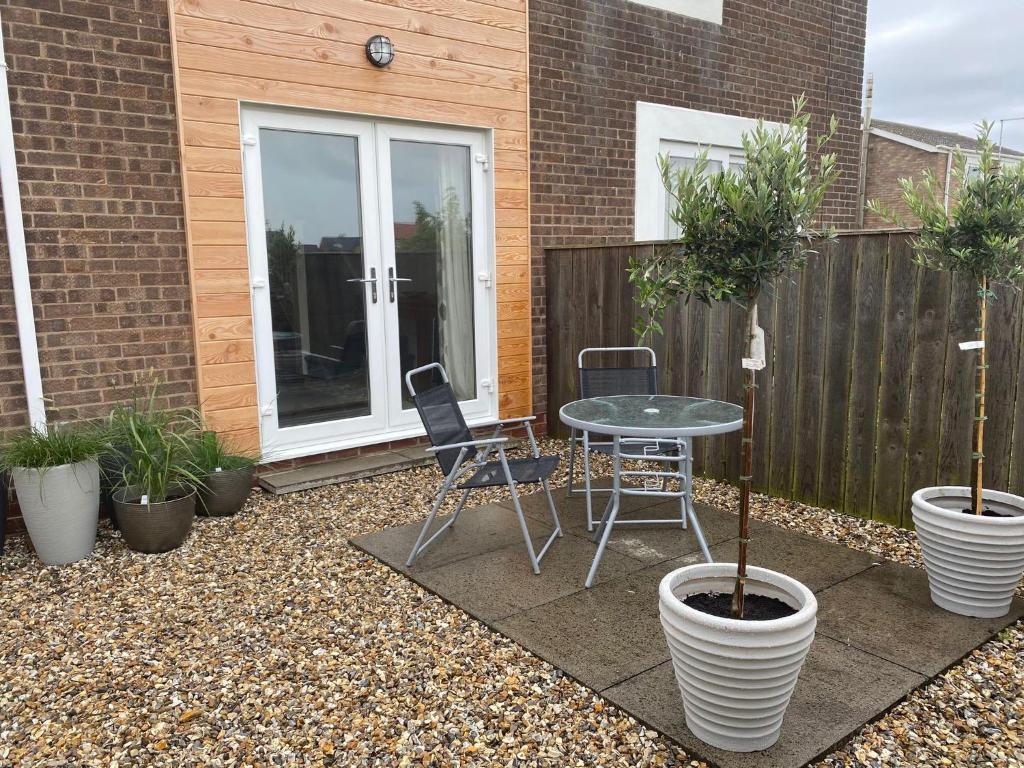 a patio with a table and chairs and potted plants at Moonstone in Beadnell
