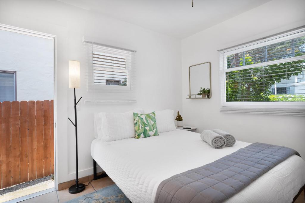 a white bedroom with a bed and two windows at Cactus Room - Private Entrance in Santa Barbara