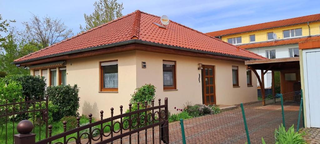 una casa con techo rojo y valla en Ferienhaus am Kulkwitzer See en Leipzig