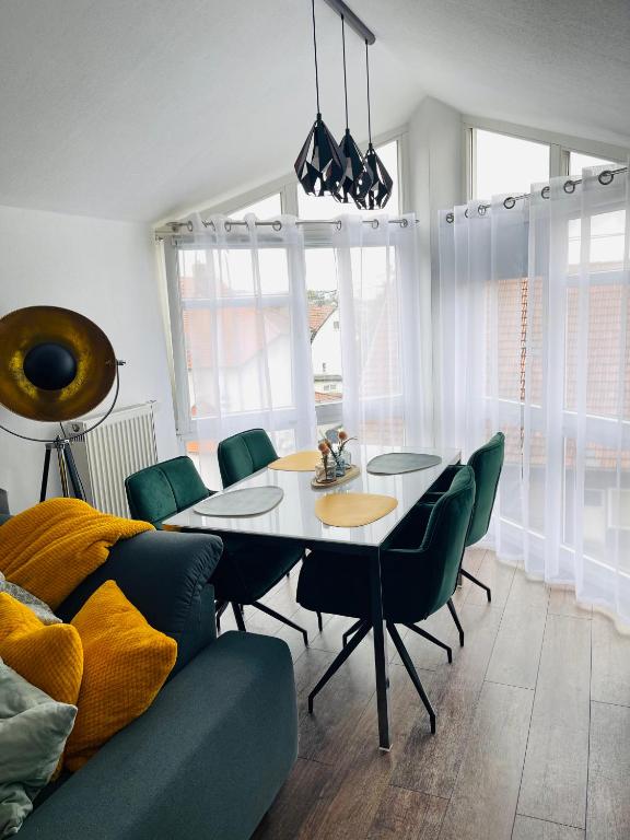 a dining room with a table and green chairs at Ferienwohnung Moments klimatisiert in Balingen