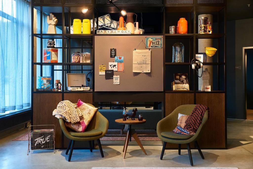 two chairs and a table in a room at Moxy Essen City in Essen