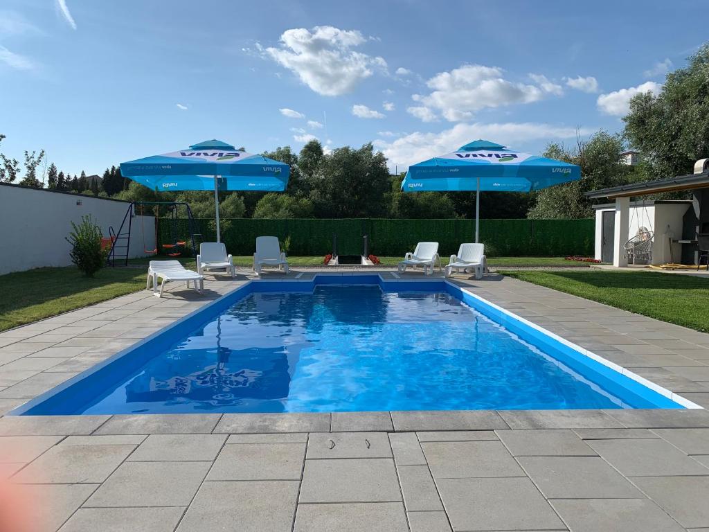 a swimming pool with two blue umbrellas and two chairs at Sweet Retreat on Buna Riverside - with private pool in Blagaj
