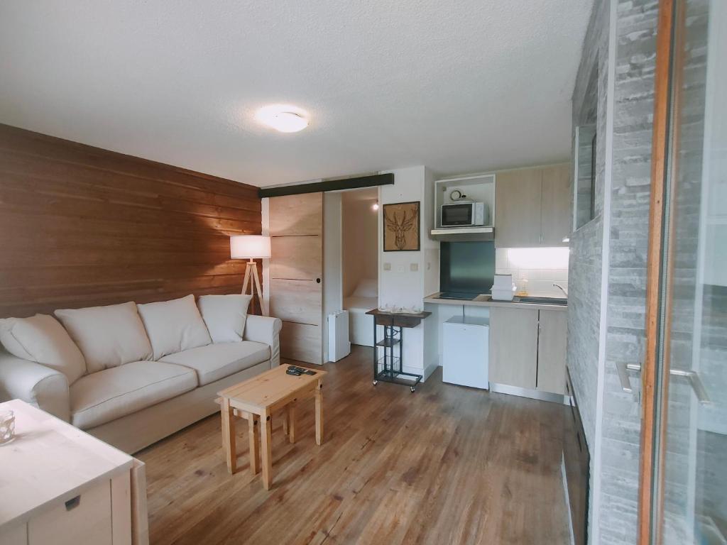 a living room with a white couch and a kitchen at Au petit Payolle - Appartement type Chalet sur le Lac de Payolle in Campan