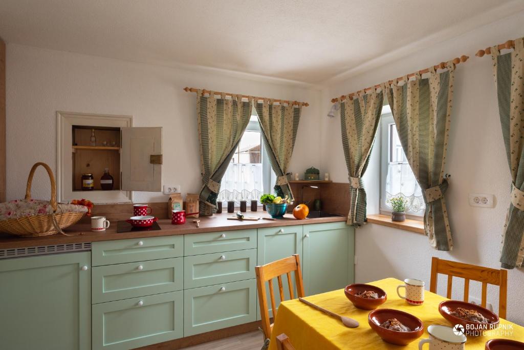 a kitchen with green cabinets and a table with a yellow table cloth at Cherry house - cosy house - ideal for bear watching, in the neighborhood of the medieval Snežnik castle in Stari Trg pri Ložu