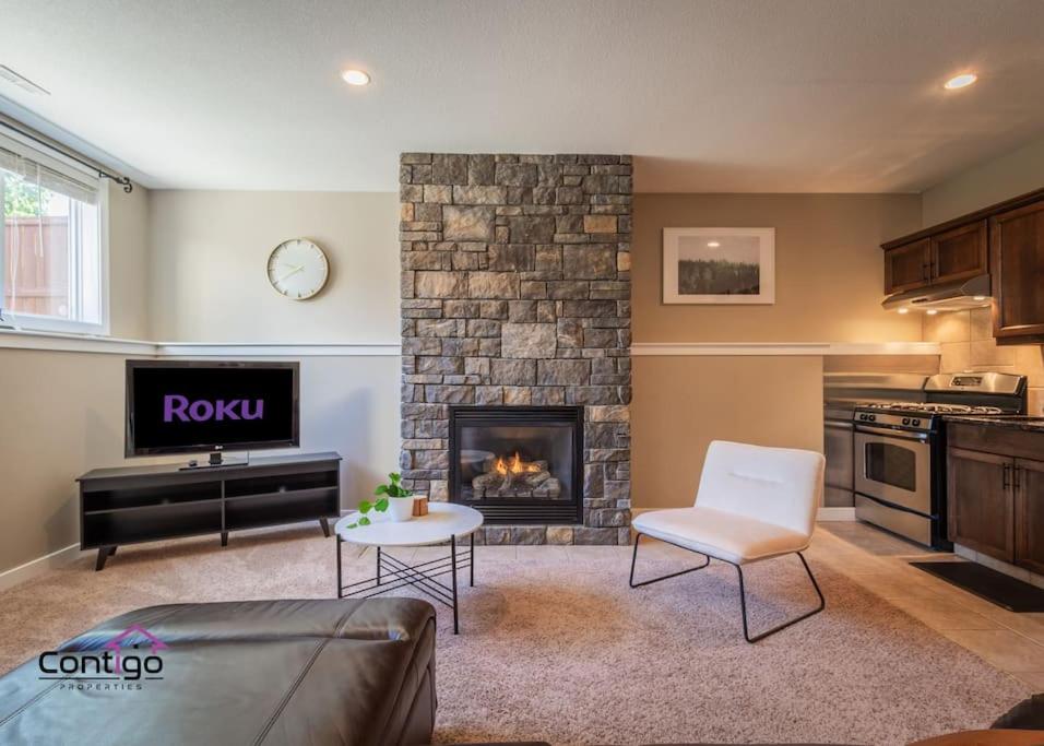 a living room with a fireplace and a table and a couch at Peaceful 2 BD Oasis, Bsmt Suite, Private Terrace, Near YQL in Lethbridge