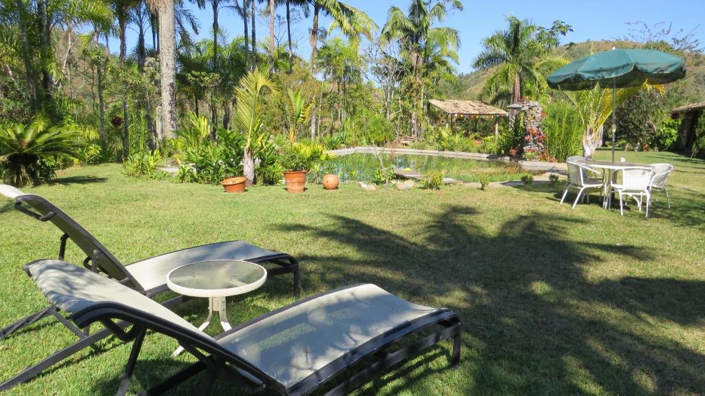 a yard with chairs and a table and an umbrella at Fazenda Maria Faceira in Monteiro Lobato