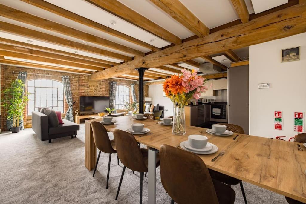 uma sala de estar com uma grande mesa de madeira e cadeiras em Wild Roses Serviced Apartments - ExCel Warehouse 2 em Londres