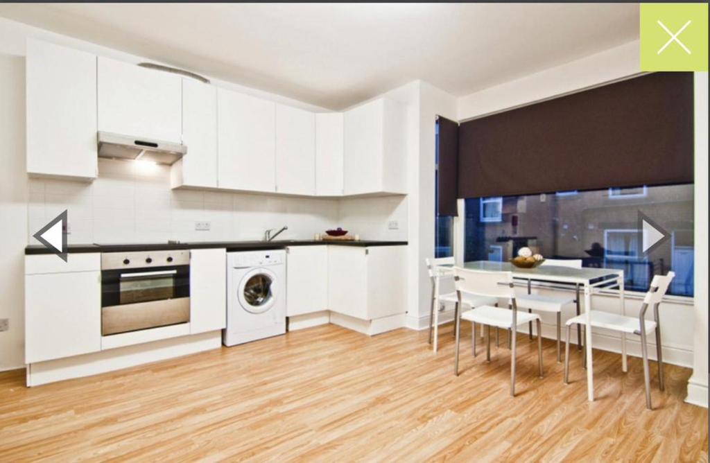 a kitchen with white cabinets and a table and chairs at Private Room close to Leeds University and City centre in Leeds